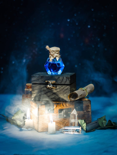 Poción mágica azul con humo, velas, cielo estrellado en caja de madera. Concepto de magia oscura
 - Foto, imagen