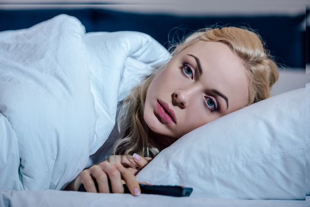 selective focus of beautiful upset woman covered in blanket and lying in bed at home - Photo, Image