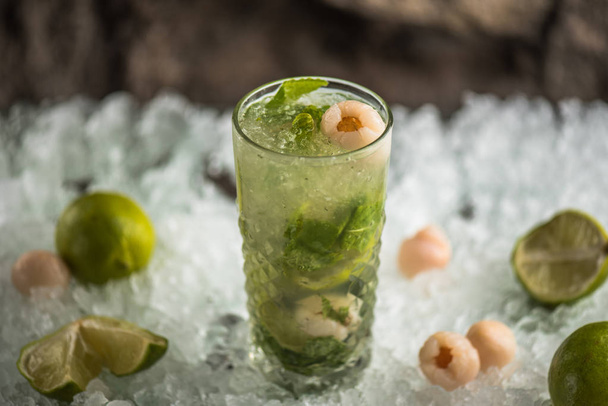 Cocktail with lime, lychee and flowers in glass on ice with ingredients - Foto, immagini