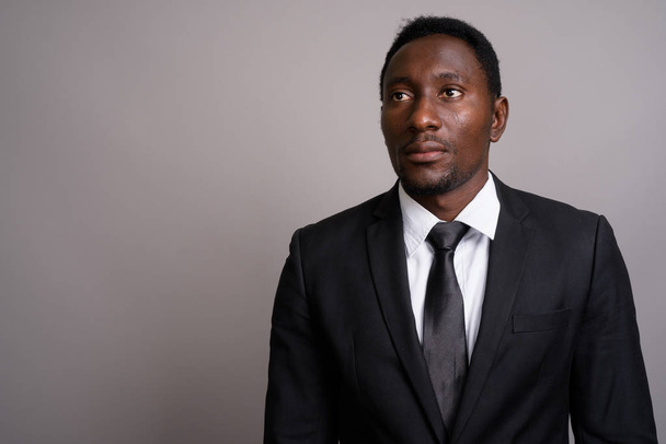 Junger gutaussehender afrikanischer Geschäftsmann vor grauem Hintergrund - Foto, Bild