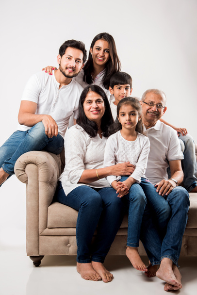 Heureuse famille indienne assise sur un canapé ou un canapé sur fond blanc  - Photo, image