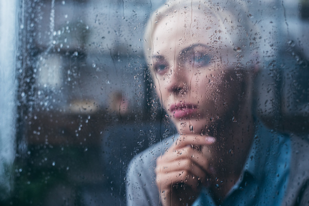 triste mujer adulta pensativo tocar la cara en casa a través de la ventana con gotas de lluvia
 - Foto, Imagen