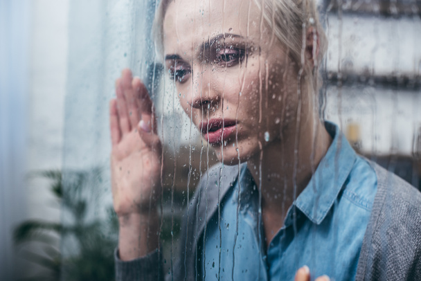 depressed adult woman touching window with raindrops - Foto, Bild