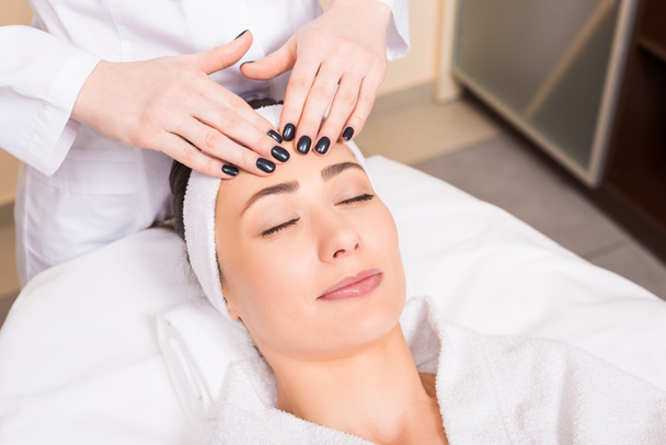 estetista facendo massaggio facciale manuale alla donna sdraiata al salone di bellezza
 - Foto, immagini