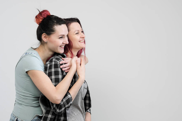 Two girls hug on a white background. Homosexual lesbian couple. Casual clothes. - Fotografie, Obrázek