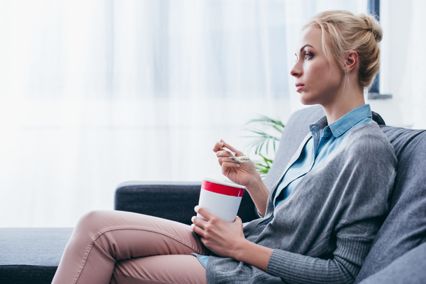 triste mujer comiendo helado mientras siitng en sofá en casa solo con espacio de copia
 - Foto, Imagen