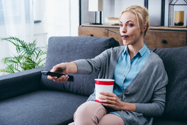 женщина ест мороженое во время сидя на диване и Wathicng телевизор дома в одиночку
 - Фото, изображение