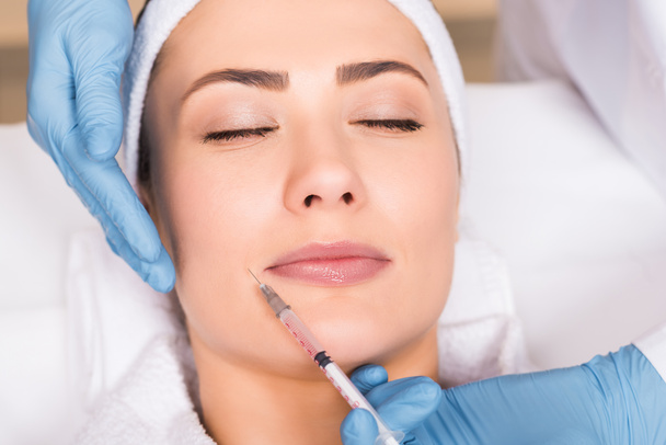 bovenaanzicht van schoonheidsspecialiste maken van injectie op gezicht van de vrouw op de salon van de schoonheid - Foto, afbeelding