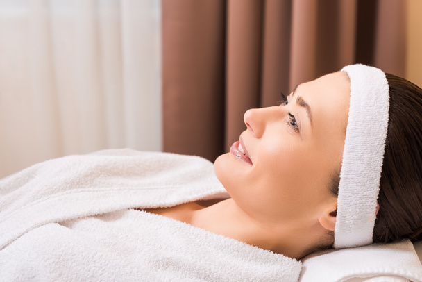 woman lying in white bathrobe and smiling at beauty salon - Fotoğraf, Görsel