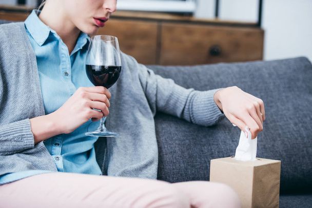 vista cortada da mulher sentada com copo de vinho tinto e caixa de tecido em casa
 - Foto, Imagem