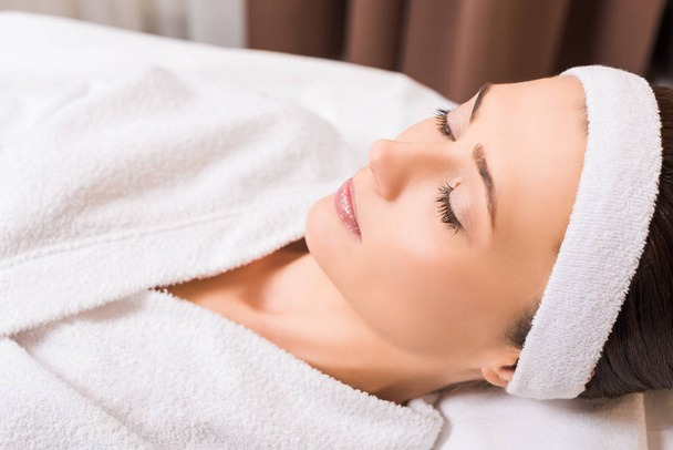 Nainen makaa valkoinen kylpytakki ja suljetut silmät kauneushoitola
 - Valokuva, kuva