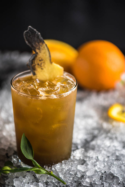 Orange cocktail decorated with ginger slice on top on ice - 写真・画像