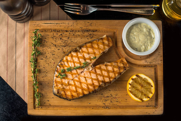 Grilled piece of salmon on wooden board with dip and lemon - Foto, Imagen