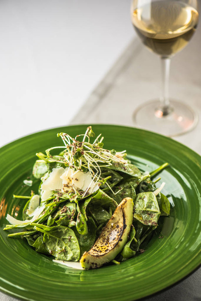 Fresh vegetable salad with grilled avocado served on green plate - Photo, Image