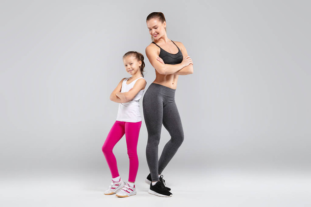 Urheilullinen kaunis nainen ja hänen tyttärensä poseeraa kameran edessä
 - Valokuva, kuva