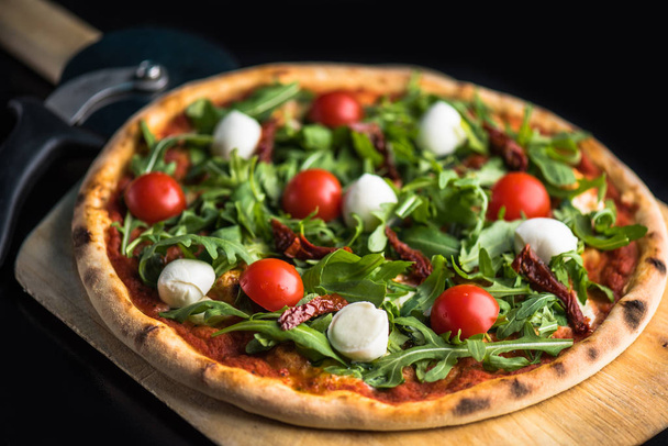 pizza with fresh tomatoes, arugula and mozzarella cheese on wooden  - Photo, Image