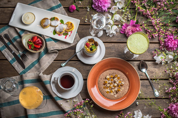 Colazione tavolo in legno con piatti sani e fiori
 - Foto, immagini