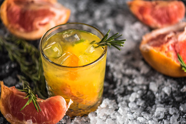 Cocktail in glass with grapefruit and rosemary on dark background with ice - 写真・画像