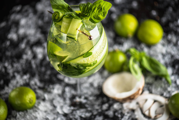 Cocktail with basil, lime and coconut in glass on dark background with ice - Photo, image