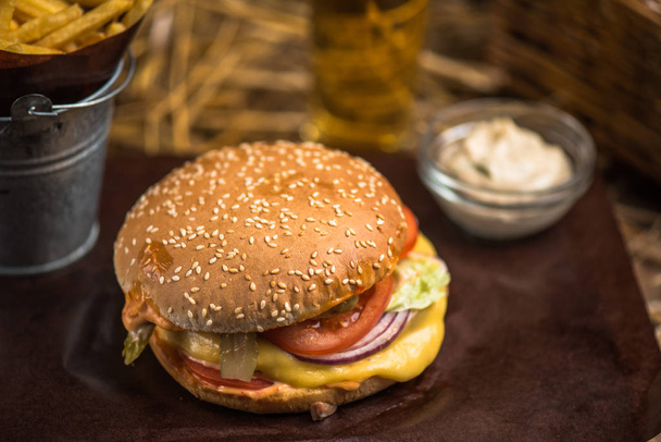 Tasty burger with french fries on wooden board - 写真・画像