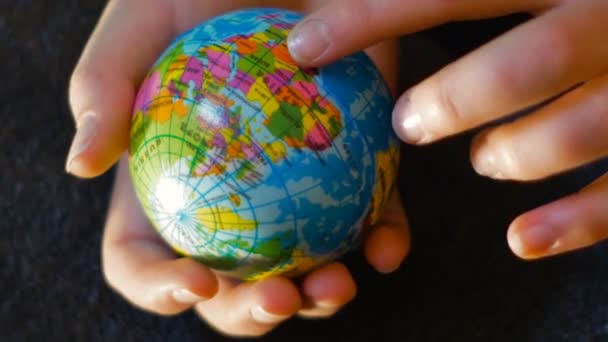 a teenage girl holds a mini globe in her hand, with her hand pointing to Africa, footage suitable for telling migration phenomena in a simple way - Záběry, video