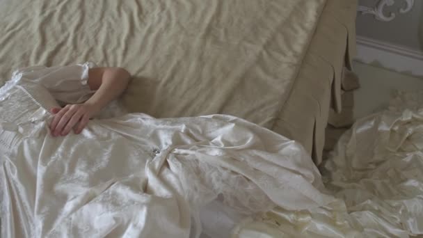 Młoda piękna kobieta w strój rocznik piłka, leżąc na łóżku ogromne złote i myślenia przy macha z Pióro wentylatora - Materiał filmowy, wideo