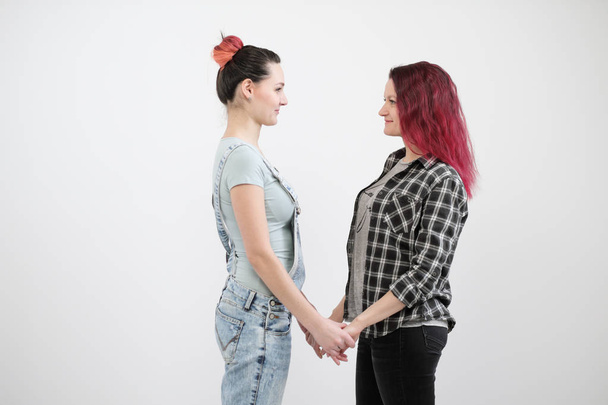 Two girls hug on a white background. Homosexual lesbian couple. Casual clothes. - Фото, зображення