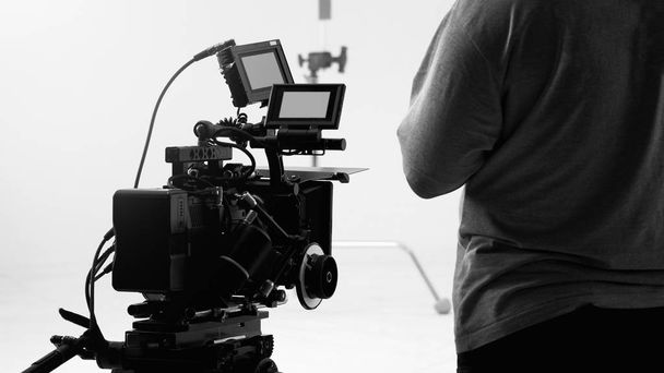 За видеокамерой, которая записывает онлайн коммерческий или веб-фильм в большой студии производства с профессиональным оборудованием, таким как камера высокого разрешения и мониторы и светодиодный свет с командой - Фото, изображение