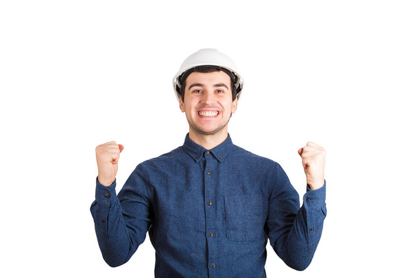 Felice allegro giovane ingegnere indossa casco protettivo tenendo i pugni fino a celebrare il successo isolato su sfondo bianco
. - Foto, immagini