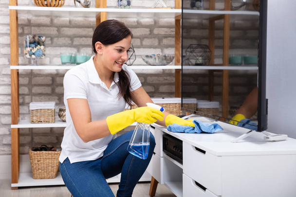 Smiling Young Woman Cleaning Furniture With Napkin - Foto, Bild
