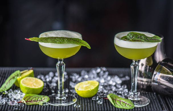 Alcohol sour green cocktail served in glasses on bar counter - Fotó, kép