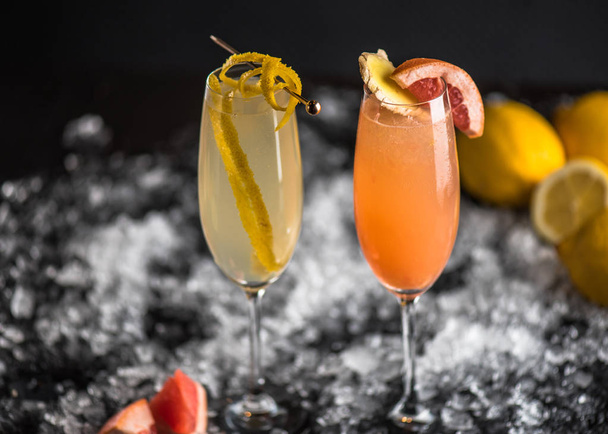 Cocktails in glasses, grapefruit, lemon and ginger on ice on dark background. Fresh close up drinks - Photo, Image