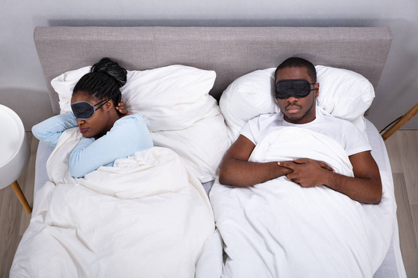 Young African Couple Sleeping On Bed Using Eye Mask In Bedroom - Foto, afbeelding