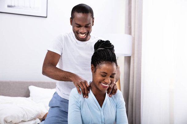 Happy Young African Man Giving Shoulder Massage To His Wife In Bedroom - Zdjęcie, obraz