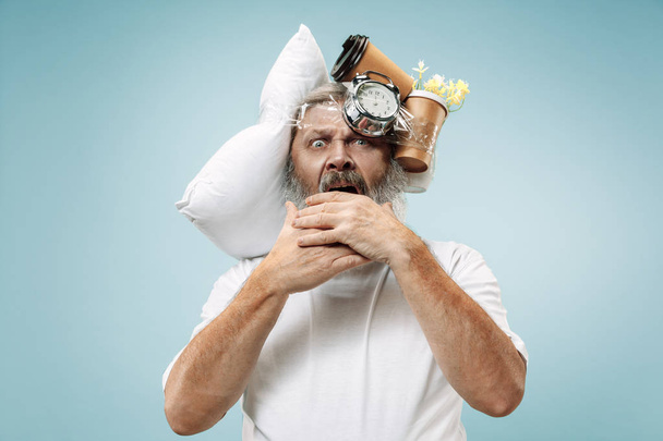 Tired man sleeping at home having too much work. Bored businessman with pillow and hourglass - Foto, imagen