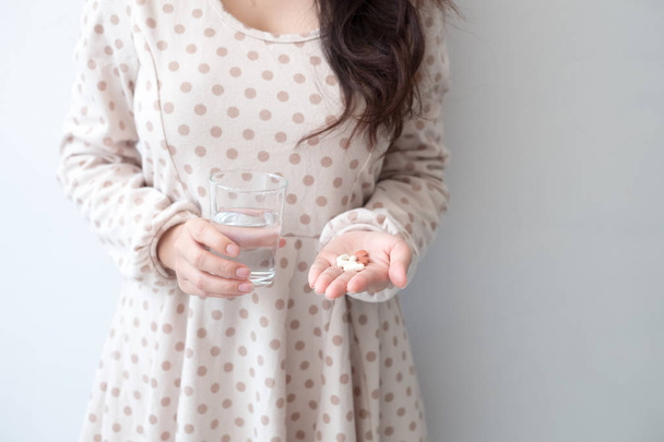 A woman holding a medicine and a glass of water in her hand. Medical and health concepts - Photo, Image