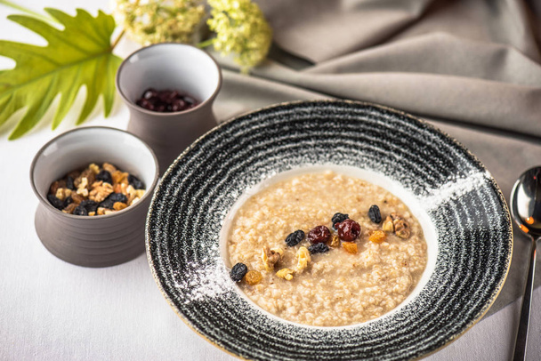 Porridge in plate with nuts and raisins for breakfast - Foto, Imagen