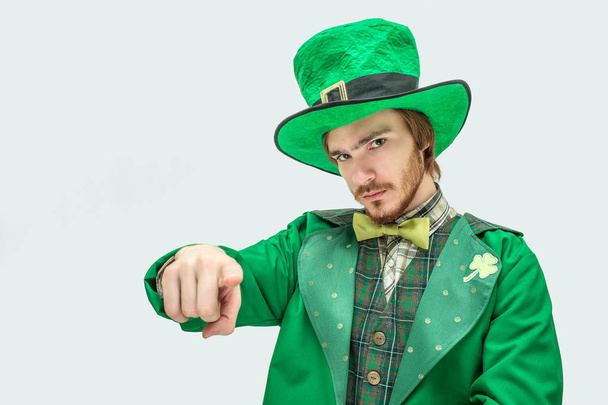 Serious young man in green suit point straight on camera. He wear St. Patricks costume. Isolated on grey background. - Foto, Bild