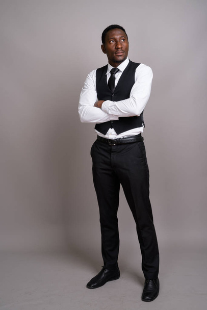Young handsome African businessman against gray background - Foto, Imagem