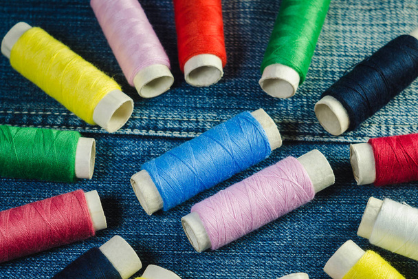 Bobinas de hilo de coser azul, blanco, rosa, rojo y verde en denim
 - Foto, Imagen