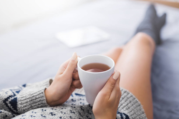Woman resting in bed with cup of tea - Photo, image