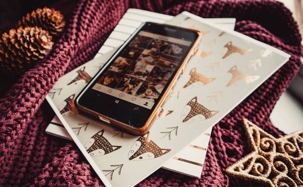 Teléfono y bloc de notas sobre fondo de madera con decoraciones navideñas - Foto, Imagen