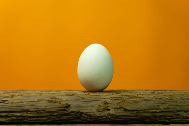 Huevo sobre una vieja mesa de madera de roble fondo naranja
. - Foto, imagen