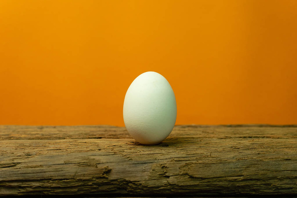 Uovo su un vecchio tavolo di legno di quercia sfondo arancione
. - Foto, immagini