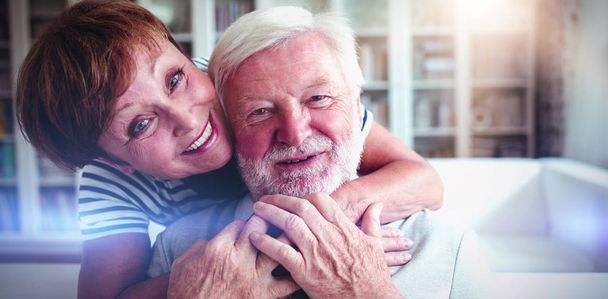 Portrait of senior woman embracing man in living room - Foto, Bild