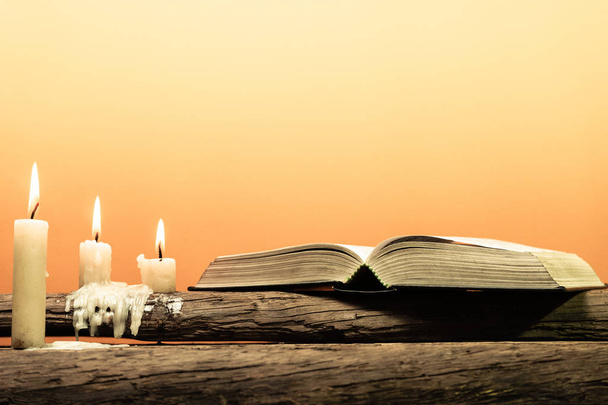 Szent Biblia, egy öreg tölgy fából készült asztal. Gyönyörű narancssárga háttérrel. A vallás fogalma. - Fotó, kép