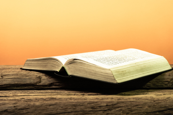 Священная Библия на старом деревянном столе из дуба. Красивый оранжевый фон. Концепция религии
. - Фото, изображение