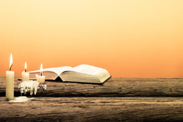 Holy Bible on a old oak wooden table. Beautiful orange background. Religion concept. - Photo, Image