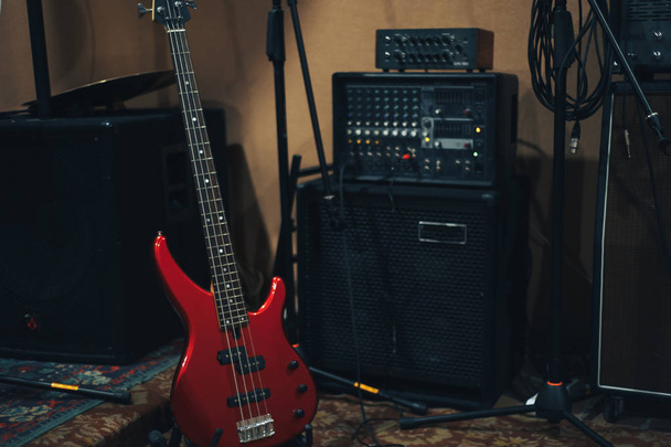 Red bass guitar on a home musical studio background. - Zdjęcie, obraz