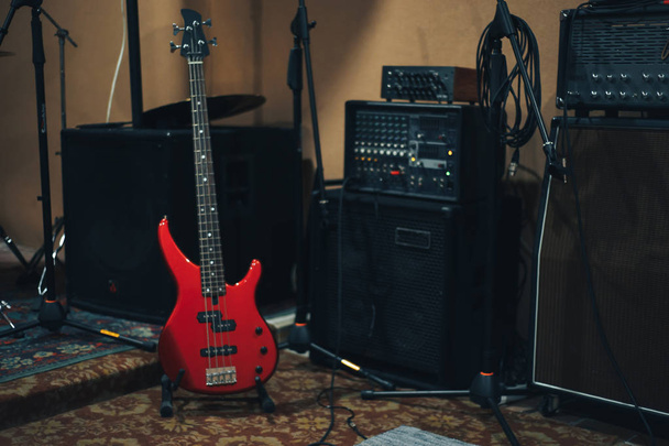 Guitarra baixo vermelho em um fundo estúdio musical em casa
. - Foto, Imagem